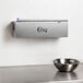 A silver stainless steel film and foil dispenser and cutter on a counter.