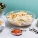 A pebbled serving bowl filled with chips.