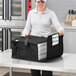 A woman holding a black Choice insulated pizza delivery bag with white pizza boxes inside.