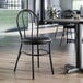 A Lancaster Table & Seating black metal hairpin chair with a black vinyl seat detached from the chair.