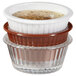A stack of white fluted plastic ramekins with food in them.