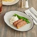 An Acopa ivory stoneware platter with meatloaf and green beans with a fork and knife on a napkin.