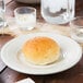 An ivory china bread and butter plate with a roll of bread on it.