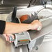 A person using a Hobart meat slicer to cut meat on a counter.