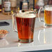 A Libbey pitcher of beer on a counter with a glass of beer.