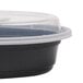 A black plastic Pactiv Newspring VERSAtainer oval container with a clear lid.