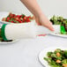 A hand pouring white liquid from a Carlisle white cylinder into a salad.