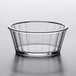 A clear plastic fluted ramekin on a white surface.