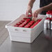A person putting red caps into a white Channel white polyethylene lug.