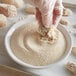 A person in gloves using J.O. Oyster and Fish Breader to mix food in a bowl.