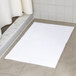 A white Oxford Belleeza bath mat on a tile floor.