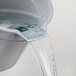 A person pouring water into a Rubbermaid gray round bucket.