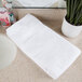 An Oxford Belleeza white bath towel on a white counter.