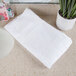 An Oxford Belleeza white bath towel on a white countertop.