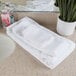 A bathroom counter with a stack of white Oxford Belleeza hand towels.