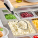 A person using a Vollrath black solid oval spoodle to serve mashed potatoes.