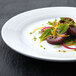 A round white porcelain plate with a salad on it.