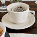 A Oneida cream white china saucer with a cup of coffee on it.