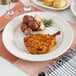 A close-up of Oneida Espree cream white china plate with food on a table.