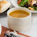 A Oneida Odyssey bouillon cup filled with soup next to a plate of salad.