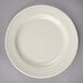 A Oneida cream white china plate with a rim on a gray surface.