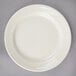 A Oneida Espree cream white china plate on a gray surface.