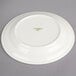 A white Oneida china plate with green text reading "Espree" on it.
