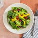 A Oneida cream white china plate with a salad of spinach, cranberries, and mango.