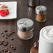 A Tablecraft spice shaker on a table with coffee and food.