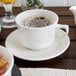 A Oneida cream white china cup on a saucer.