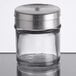 A Tablecraft spice shaker with adjustable metal lid on a table.