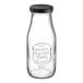 An Acopa glass milk bottle with a black lid.