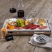 A Frilich stainless steel rectangular cooling plate with food on it displayed on a table.
