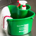 A San Jamar green cleaning caddy with a spray bottle inside.