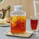 An Anchor Hocking glass pitcher filled with iced tea and lemons on a counter.