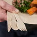 A hand holding a Bambu Veneerware wooden spoon.