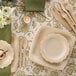 A table setting with a Bambu Veneerware disposable bamboo spoon, fork, and knife on a table with plates and cutlery.