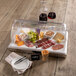 A Frilich rectangular plastic roll top cover on a table with food on it.