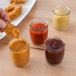 A person holding a fried chicken piece and dipping it into a jar of sauce using an Acopa Beer Tasting Glass.