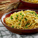 A white bowl of Little Barn Homemade Medium Egg Noodles with peas.