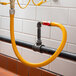 A yellow Regency gas connector hose connected to a black pipe.