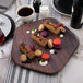 A Rosseto walnut melamine polygon tray with desserts, coffee, and drinks on it.