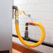 A yellow Regency gas connector hose connected to a metal pipe.