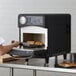 A man cooking food in a TurboChef Sota rapid cook oven on a countertop.