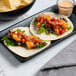 A plate with two shrimp tacos made with Mission White Corn Tortillas on a table.