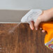 A person using Arm & Hammer hard surface cleaner to spray a table.