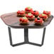 A Rosseto walnut melamine polygon tray with fruit on it and a metal riser holding it.