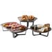 A Rosseto walnut polygon tray with a variety of food including meat, fruit, and cheese on a hotel buffet table.