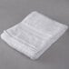 An Oxford Reserve white hand towel on a gray surface.