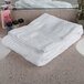 A stack of Oxford Reserve white bath towels on a white surface.